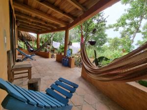 een patio met stoelen en hangmatten op een huis bij Posada La Sabila in Mazunte