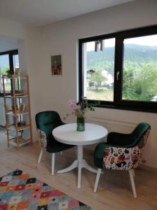 una stanza con un tavolo, delle sedie e una finestra di BELCARA Apartment a Buşteni