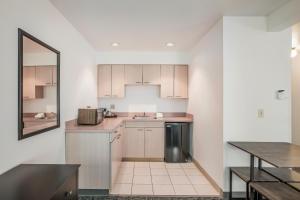 an empty kitchen with white cabinets and a table at Americas Best Value Inn & Suites-Birch Run in Birch Run