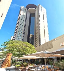 two tall buildings with tables and umbrellas in a courtyard at Staybridge Suites São Paulo, an IHG Hotel in Sao Paulo