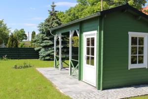 a green shed with a white door on a lawn at Ferienwohnung Zum Alten Gaswerk in Gräfenhainichen