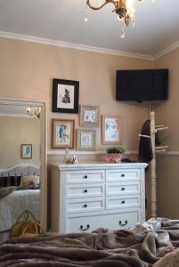 una camera da letto con cassettiera e TV a parete di FLAT DE CHARME RÚSTICO EM GRAMADO a Gramado Altre 4 foto