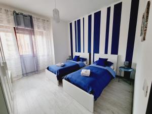 two beds in a bedroom with blue and white at Enne's Apartments in the heart of Palermo in Palermo