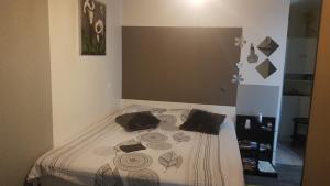 Cama en habitación con colcha y almohadas en Chambre chez l habitant...maison Zen Zen, en Brévonnes