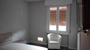 1 dormitorio con una silla blanca y una ventana en casa serrati(locanda la cascina)camera con bagno privato ma cucina in comune, en San Giuliano Milanese