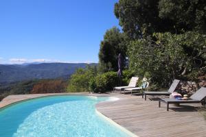 una piscina con 2 sillas y una terraza de madera en La Vela, en Peille