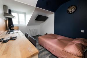 1 dormitorio con cama, mesa y reloj en NUIT BY LIGHT - Dormir Comme A La Maison en Châteaubriant