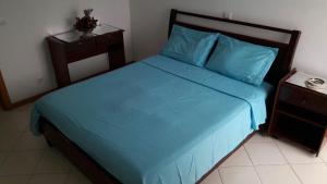 a bedroom with a blue bed and a night stand at Mar & Morna in Mindelo