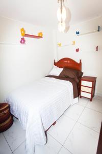 een slaapkamer met een bed met witte lakens en speelgoed aan de muur bij Beautiful Penthouse in Lima, in front of the park in Lima