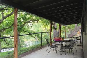 eine abgeschirmte Veranda mit einem Tisch und Stühlen in der Unterkunft The Springs Retreat in Leakey