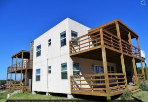 a large white building with wooden balconies on it at Elementos del diablo in Punta Del Diablo