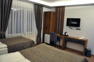 a hotel room with two beds and a desk with a television at SAKALİFE APART Otel in Erzurum
