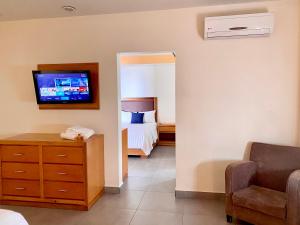 - une chambre avec un lit et une télévision murale dans l'établissement Hotel Buen Valle, à Torreón