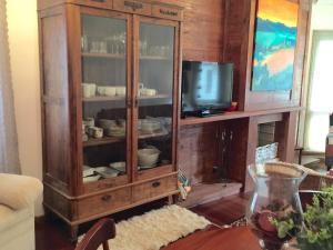 un armario de madera con TV y platos. en FLAT DE CHARME RÚSTICO EM GRAMADO, en Gramado