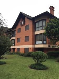 un grande edificio in mattoni con un prato di FLAT DE CHARME RÚSTICO EM GRAMADO a Gramado