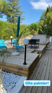 una terraza de madera con sillas y sombrilla en Carpe Diem paradise, en Mougins