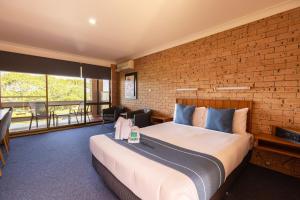ein Schlafzimmer mit einem großen Bett und einer Ziegelwand in der Unterkunft Midlands Motel in Taree