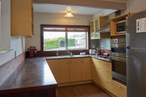 a kitchen with yellow cabinets and a large window at Fox Chalet - Lake Tekapo in Lake Tekapo