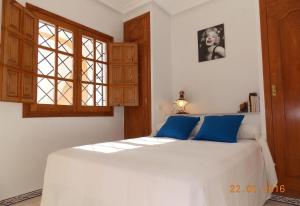 sypialnia z białym łóżkiem z niebieskimi poduszkami w obiekcie Holiday House Torre Mata w mieście Torrevieja