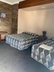 ein Hotelzimmer mit 2 Betten und einem Tisch in der Unterkunft Downtown Motel in Wollongong