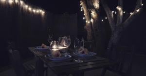 un tavolo in legno con bicchieri da vino e luci sopra di Romántico apartamento, piscina y BBQ en Playa La Tejita a El Médano