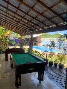 a pool table sitting under a pavilion with a swimming pool at Casa da piscina in Arraial do Cabo