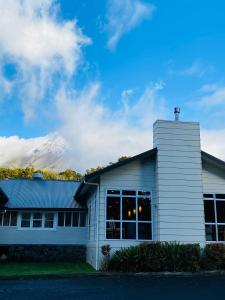 a white building with a mountain in the background at Ngati Ruanui Stratford Mountain House in Stratford