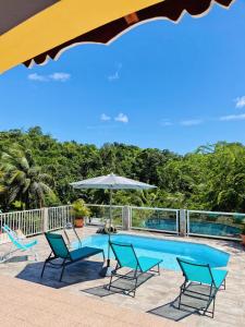 piscina con sedie e ombrellone di La Villa Ixora, magnifique Villa avec Piscine a Les Abymes