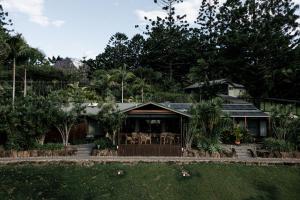 a large house with a wooden roof and trees at Cape Byron Retreat (Adults-Only) in Byron Bay