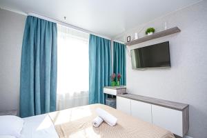 um quarto com uma cama com uma televisão e cortinas azuis em Lucky Jet em Novosibirsk