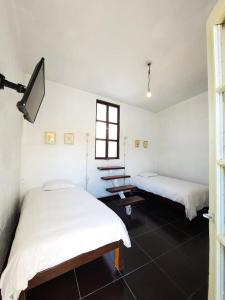 a white room with two beds and a window at El Albergue Español in Arequipa