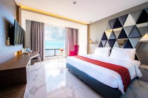a hotel room with a bed and a view of the ocean at Swiss-Belcourt Kupang in Oesapa-besar