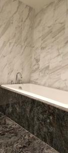a white bath tub in a bathroom with marble tiles at Relaxing condo in Falls Downtown Victoria in Victoria