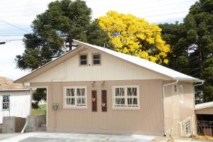 a smallige house with white windows in a driveway at Quintal das Araucárias hospedagem in São Joaquim