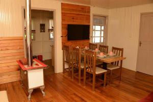 uma sala de jantar com uma mesa e cadeiras e uma televisão em Quintal das Araucárias hospedagem em São Joaquim