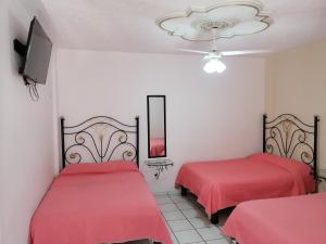 Cette chambre comprend 2 lits dans une chambre dotée de draps rouges et d'une télévision. dans l'établissement Hotel Providencia, à Talpa de Allende
