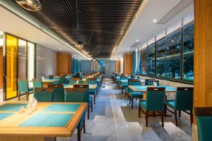 a dining room with tables and chairs and windows at Huangshan Tiandu International Hotel in Huangshan