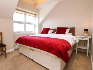 a bedroom with a red and white bed with a window at Royal Manor Park in Llandudno