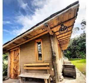 uma pequena cabana de madeira com um banco à sua frente em El Tio Hostal em Otavalo
