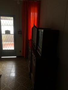 uma sala de estar com televisão e janela em !Penha casa toda mobiliada para temporada no Rio de Janeiro