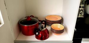einem Schrank mit einem roten Topf und einem Stapel Teller in der Unterkunft CASA VISTA HERMOSA in Baños