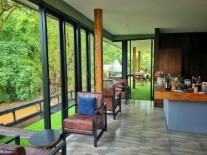 a living room with chairs and a counter and windows at AomlongHomenon(อมลอง โฮมนอน) in Ban Bong