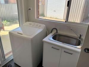 a small kitchen with a sink and a washing machine at Tranquil Waters in Busselton