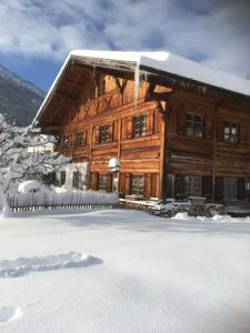 Casa de madera grande con nieve en el suelo en Ferienwohnung Schankwirtschaft Wohlfart en Pfronten