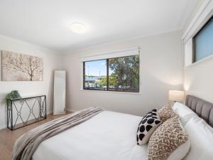 a bedroom with a bed and a window at Ocean Breeze Townhouse in Coffs Harbour