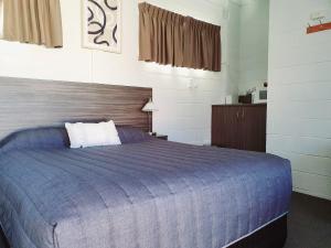 a bedroom with a bed with a blue comforter at Motel Riverbend in Tailem Bend