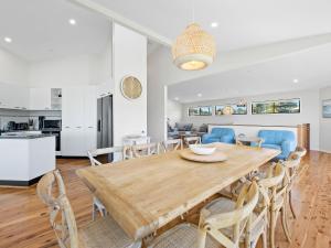 eine Küche und ein Esszimmer mit einem Holztisch und Stühlen in der Unterkunft Yabbarra Beach House in Dalmeny