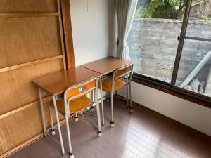 stół i krzesła w pokoju z oknem w obiekcie 昭和の家ume w mieście Fukushima
