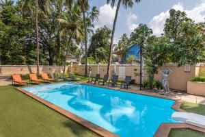 a swimming pool at a resort with chairs and palm trees at Villa Calangute Phase 4 in Calangute