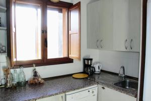 cocina con armarios blancos, fregadero y ventana en El Camino del Arcipreste, en Otero de Herreros
